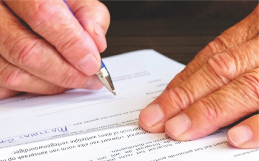 close up of someone's hands signing a document