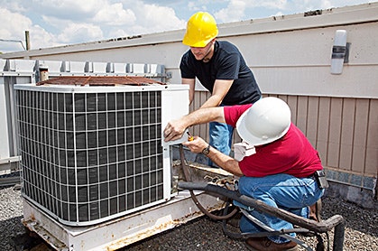 two men working on an air conditioning unit on a roof